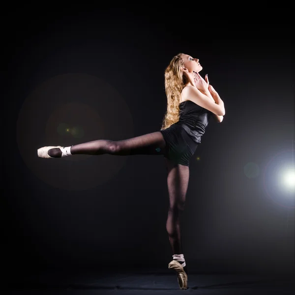Ballerina dancing in the dark studio — стокове фото