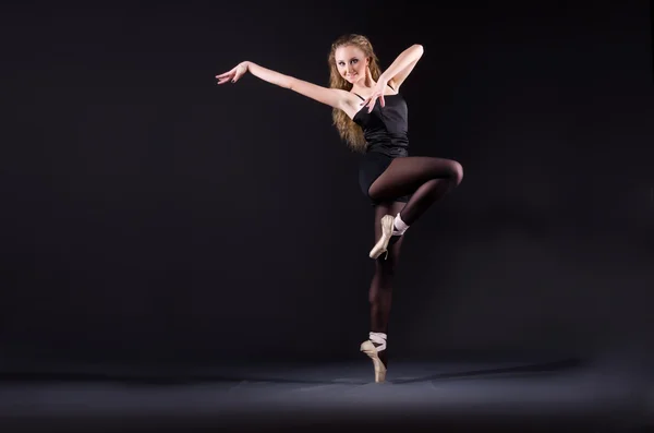 Балерина танцует в темной студии — стоковое фото