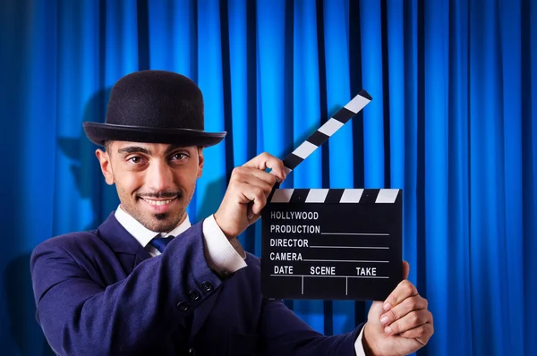 Hombre con película clapper en fondo de cortina —  Fotos de Stock