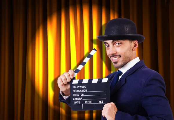 Man with movie clapper on curtain background — Stok Foto