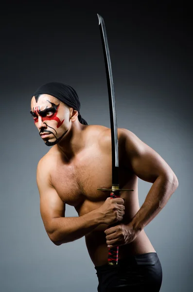 Человек с мечом и краской на лице — стоковое фото