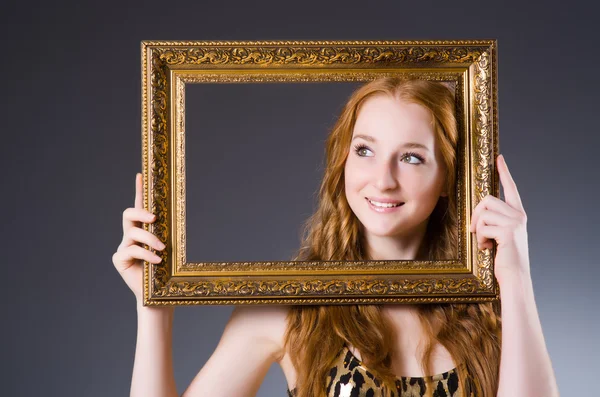 Redhead with picture frame against dark background — Stock Photo, Image