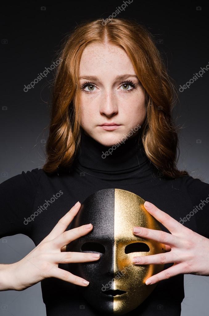 Redhead woman with mask in hypocrisy consept against black  background