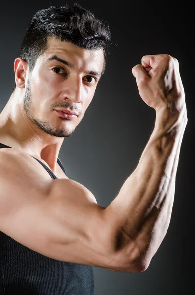 Muscular man posing in dark studio — Stock Photo, Image