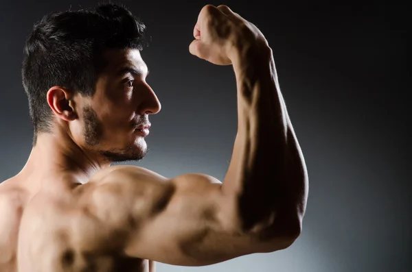 Muscular man posing in dark studio — Stock Photo, Image