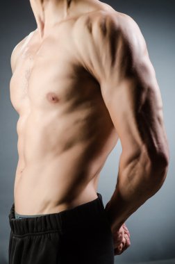 Kaslı adam karanlık stüdyoda poz veriyor.