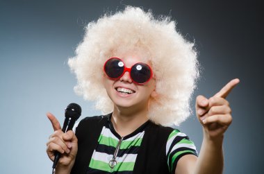 Afroperuklu adam mikrofonla şarkı söylüyor.