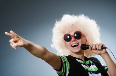 Afroperuklu adam mikrofonla şarkı söylüyor.