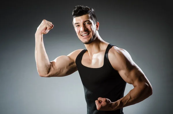 Muscular man posing in dark studio — Stock Photo, Image