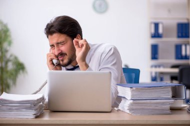 Ofisteki aşırı işten memnun olmayan genç bir erkek işçi.