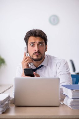 Ofisteki aşırı işten memnun olmayan genç bir erkek işçi.