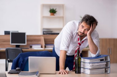 Genç alkol bağımlısı erkek çalışan ofiste çalışıyor.