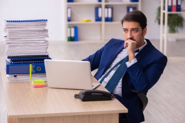 Genç bir erkek çalışan ve ofiste çok fazla iş var.