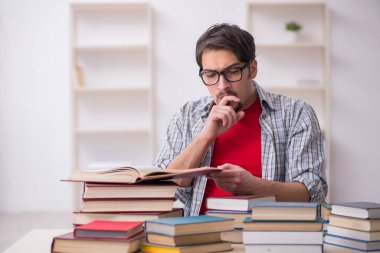 Genç bir erkek öğrenci ve sınıfta çok fazla kitap var.