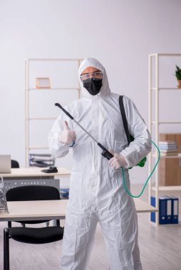 Young male contractor disinfecting office during pandemic