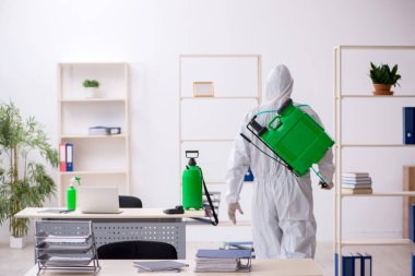 Young male contractor disinfecting office during pandemic