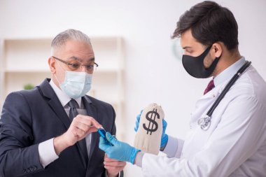 Yaşlı işadamı aşı danışmanıyla genç erkek doktoru ziyaret ediyor.