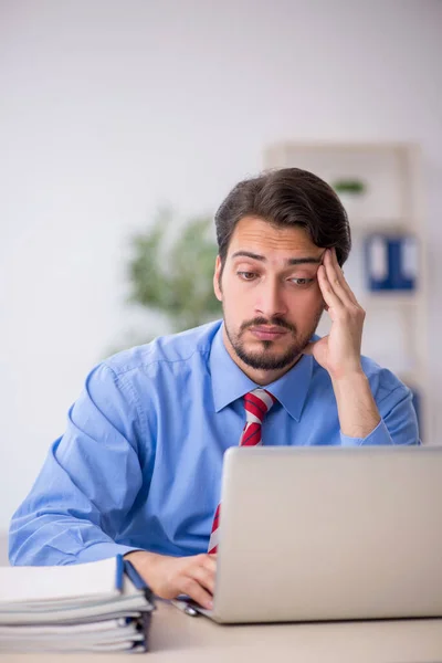 Jovem funcionário masculino infeliz com excesso de trabalho no escritório — Fotografia de Stock