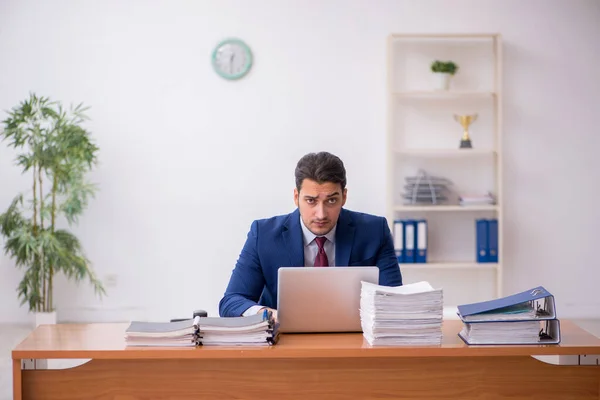 Ung affärsman och för mycket arbete på kontoret — Stockfoto