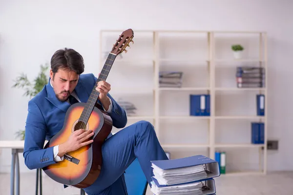 Joven empleado masculino tocando guitarra en el lugar de trabajo — Foto de Stock