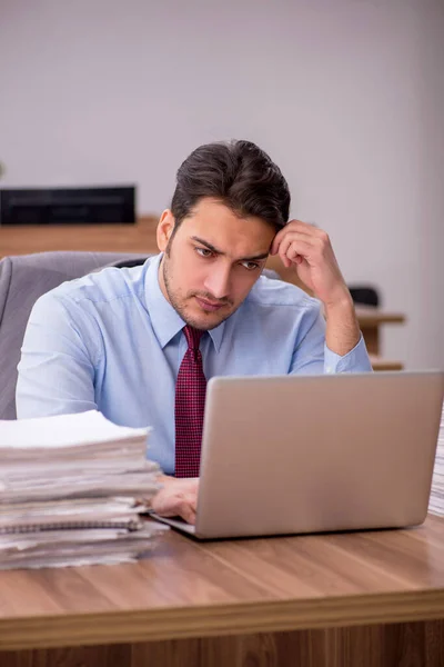 Jonge mannelijke werknemer ongelukkig met overmatig werk in het kantoor — Stockfoto