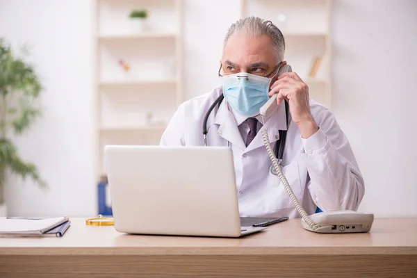 Vecchio medico maschio che lavora in clinica durante la pandemia — Foto Stock