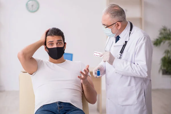 Junge männliche Patienten besuchen alten Arzt im Impfkonzept — Stockfoto