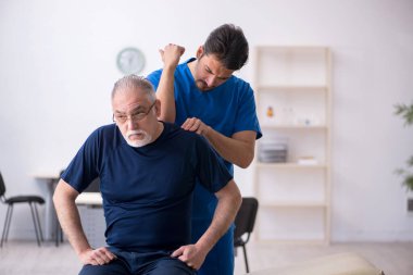 Yaşlı adam genç erkek doktoru ziyaret ediyor.