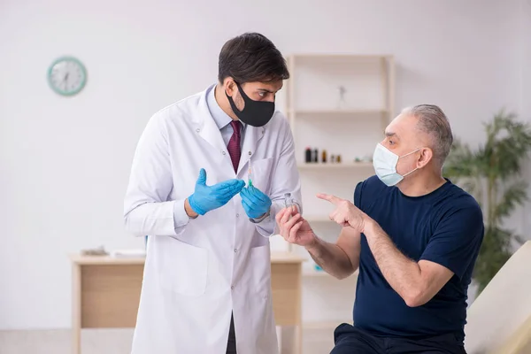 Old male patient visiting young male doctor in vaccination conce