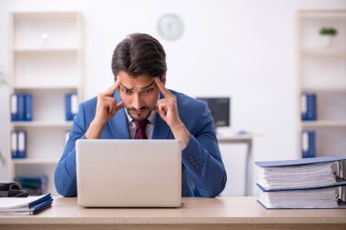 Ofisteki aşırı işten memnun olmayan genç bir erkek işçi.