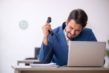 Ofisteki aşırı işten memnun olmayan genç bir erkek işçi.