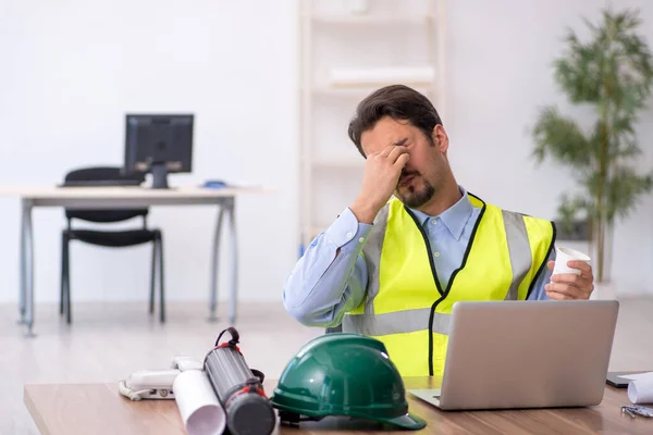 Trött ung manlig arkitekt dricker kaffe under pausen — Stockfoto