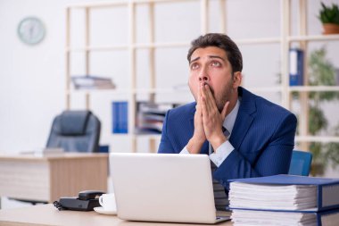 Genç bir erkek çalışan ve ofiste çok fazla iş var.