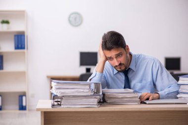 Genç bir erkek çalışan ve ofiste çok fazla iş var.