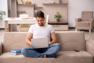 Genç erkek öğrenci salgın sırasında evde çalışıyor.