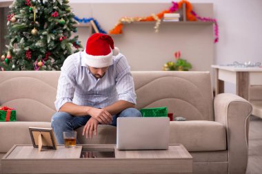 Genç adam Noel 'i evde yalnız kutluyor.