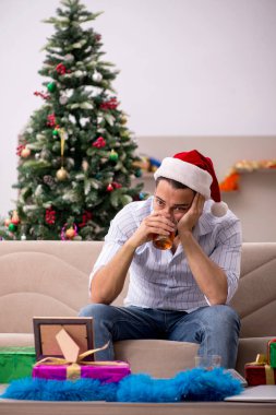 Genç adam Noel 'i evde yalnız kutluyor.