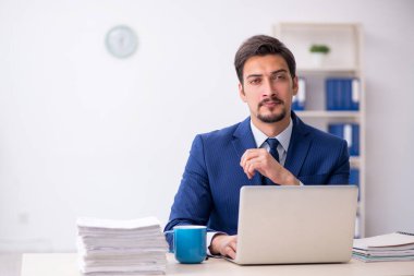 Genç bir erkek çalışan ve ofiste çok fazla iş var.