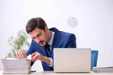 Genç bir erkek çalışan ve ofiste çok fazla iş var.