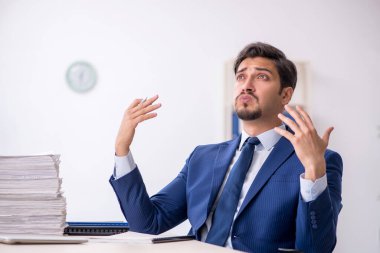 Genç bir erkek çalışan ve ofiste çok fazla iş var.