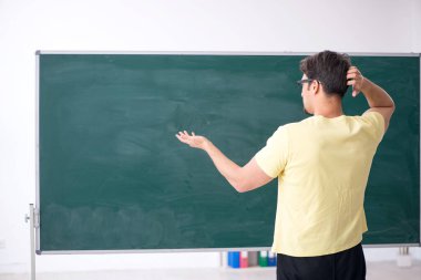 Tahtanın önünde genç bir erkek öğrenci.