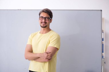 Beyaz tahtanın önünde genç bir erkek öğrenci.