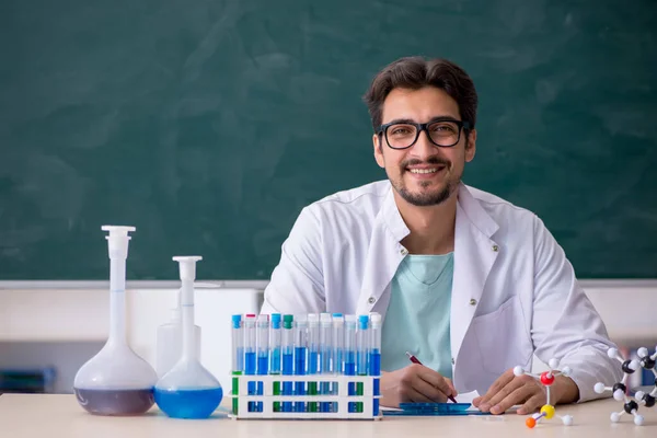 Jonge mannelijke chemicus voor schoolbord — Stockfoto