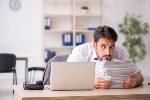 Young male employee and too much work in the office