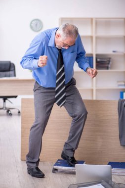 Ofisteki aşırı işten memnun olmayan yaşlı bir erkek işçi.