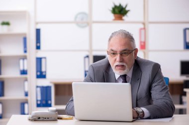 Ofisteki aşırı işten memnun olmayan yaşlı bir erkek işçi.