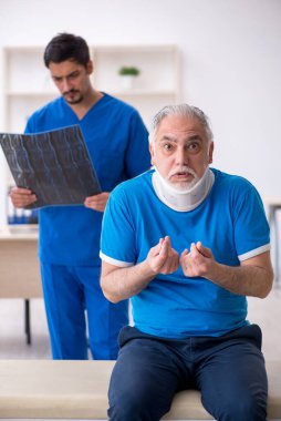 Yaşlı erkek hasta genç erkek doktor radyolojisti ziyaret ediyor.