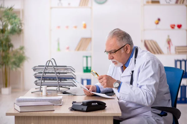 Gammal manlig läkare som arbetar på kliniken — Stockfoto