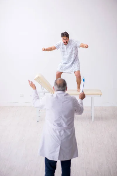 Gammal manlig läkare psykiater undersöker ung manlig patient — Stockfoto