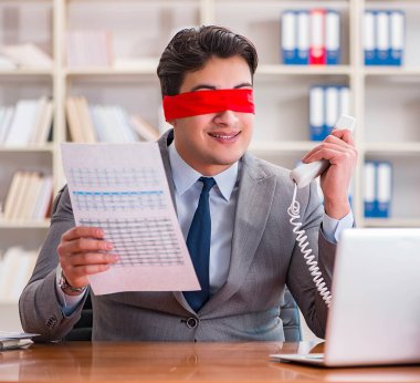 Ofiste masasında oturan gözü bağlı iş adamı.